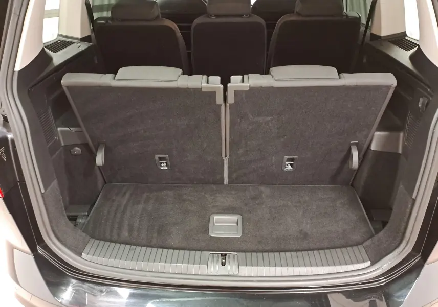 Vue arrière du coffre ouvert du Volkswagen Touran 2025 noir Grenadille, montrant la troisième rangée de sièges relevée.