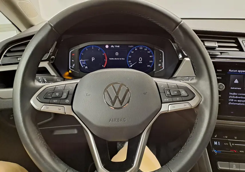 Vue rapprochée du volant noir du Volkswagen Touran 2025 avec tableau de bord digital et commandes intégrées.