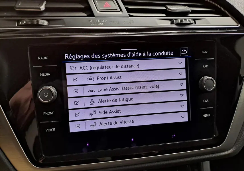 Écran tactile central du Volkswagen Touran 2025 affichant les réglages des aides à la conduite, intérieur noir.