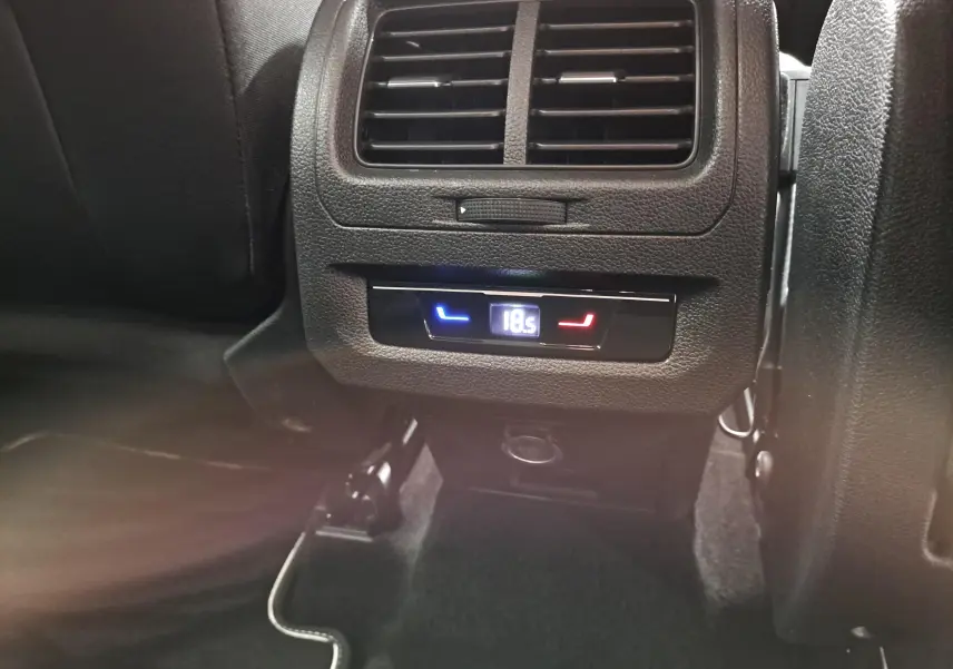 Détail de la console arrière du Volkswagen Touran 2025 noir Grenadille avec réglage numérique de la climatisation à 18,5°C.