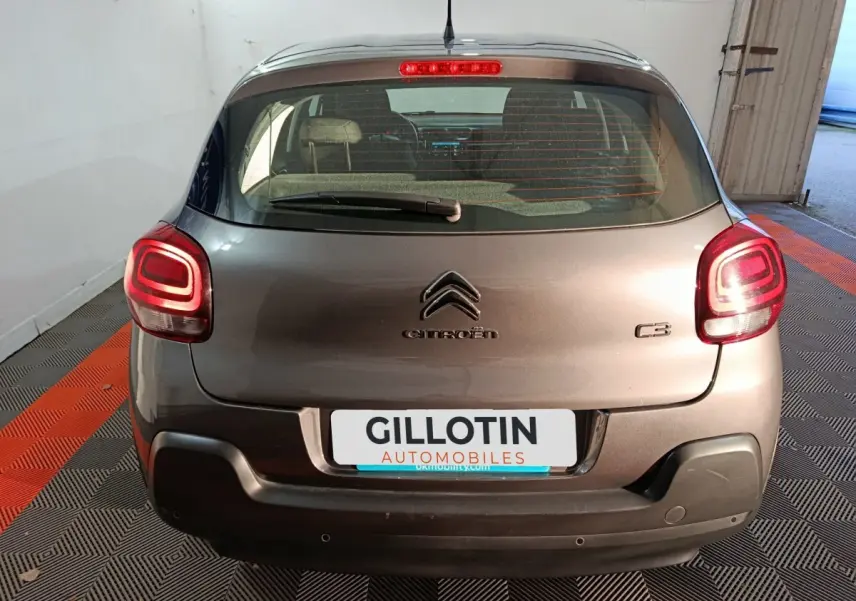 Vue arrière d'une Citroën C3 gris foncé 2024 avec feux arrière allumés et logo centré sur le hayon.