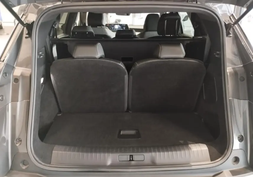 Coffre ouvert vu de l'arrière d'un Peugeot 5008 gris titanium, montrant les sièges rabattus et l'habitacle.