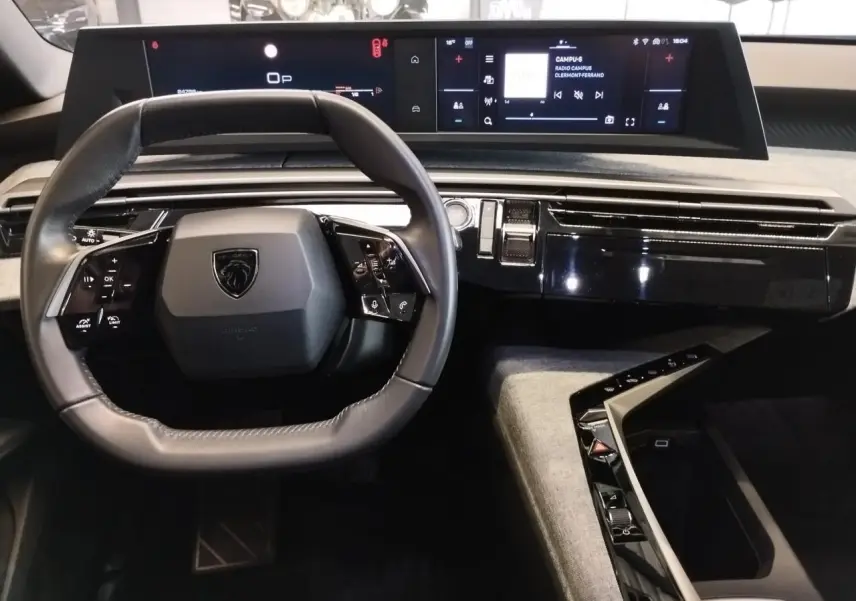 Vue intérieure du poste de conduite du Peugeot 5008 2025, volant compact noir et double écran HD panoramique.