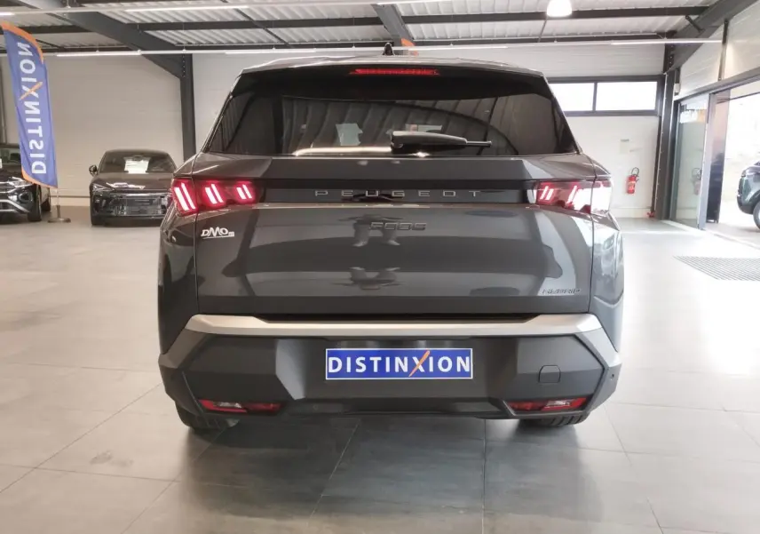 Vue arrière d’un Peugeot 5008 gris titanium avec feux arrière à LED en forme de griffes dans un showroom.