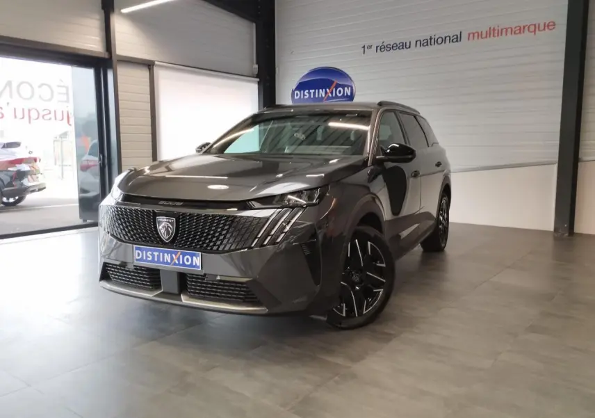 Peugeot 5008 gris titanium en 3/4 avant droit dans un showroom avec jantes alliage noires et calandre noire.
