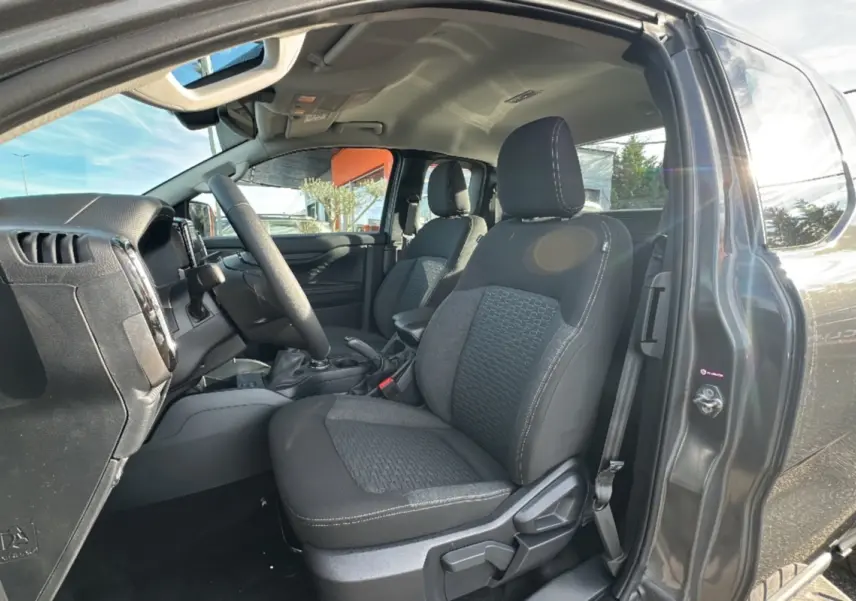Vue intérieure côté conducteur du Ford Ranger gris iconic 2025, montrant les sièges avant et le volant multifonctions en cuir.