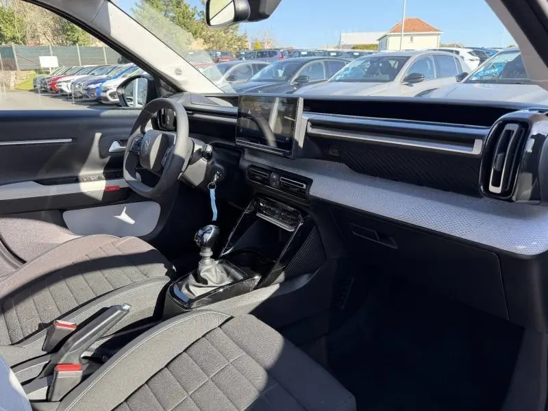 Intérieur de la Citroën C3 2025, vue côté conducteur, volant réglable, écran tactile et sellerie tissu noir.