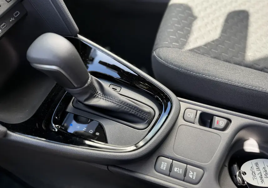 Gros plan sur la console centrale de la Toyota Yaris Cross gris atlas, montrant le levier de vitesse automatique et les commandes de conduite.
