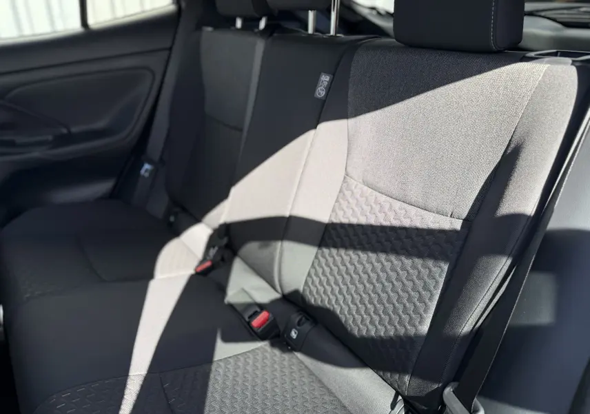 Vue rapprochée des sièges arrière en tissu gris foncé de la Toyota Yaris Cross 2026, avec ceinture de sécurité visible.