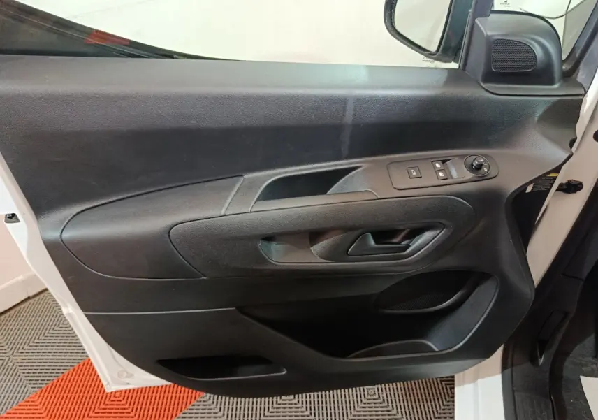 Vue intérieure côté gauche de la porte avant noire du Citroën Berlingo blanc, avec commandes électriques et poignée intégrée.