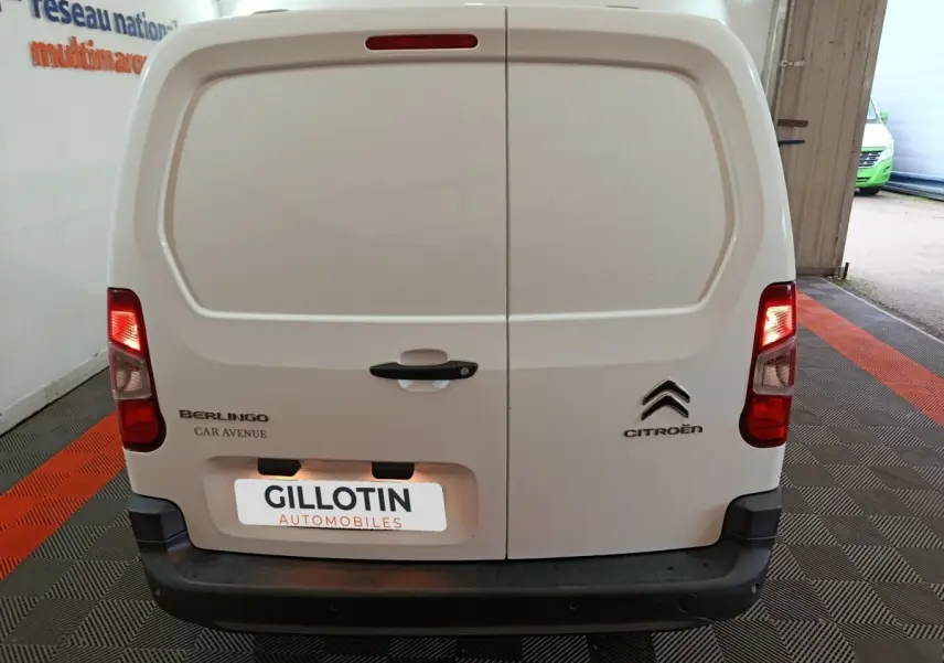 Vue arrière d’un utilitaire Citroën Berlingo blanc avec portes battantes et feux arrière allumés.