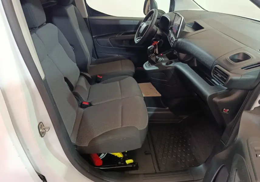 Vue intérieure côté conducteur du Citroën Berlingo blanc, montrant les sièges avant gris et le tableau de bord avec écran tactile.