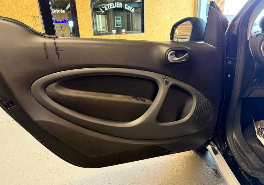 Vue intérieure de la porte avant gauche noire d'une Smart Fortwo Cabrio 2019 avec poignée et commande de vitre électrique.