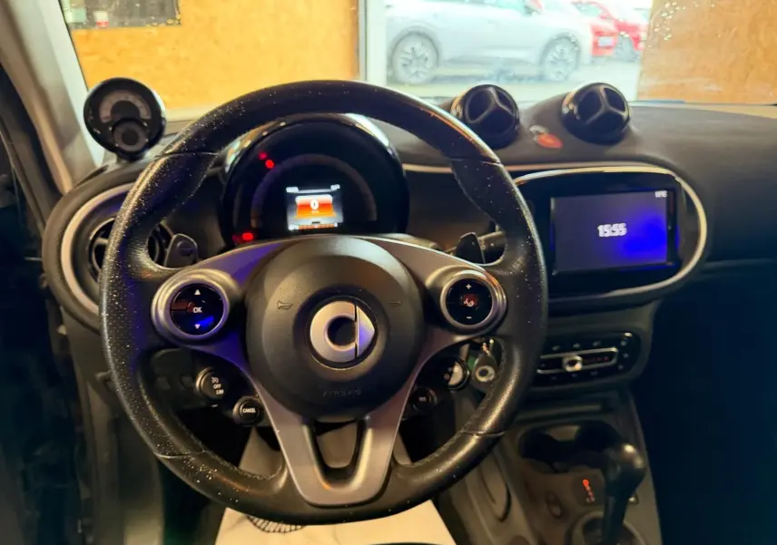 Vue intérieure centrée sur le volant multifonctions de la Smart Fortwo Cabrio 2019 avec tableau de bord et écran tactile.