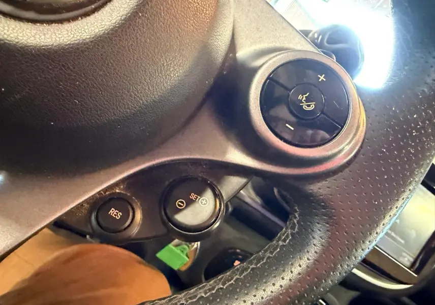 Gros plan sur le bouton de commande du volume sur le volant en cuir perforé noir d'une Smart Fortwo Cabrio 2019.