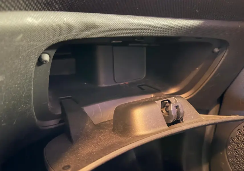 Gros plan sur la boîte à gants ouverte de la Smart Fortwo Cabrio noire, intérieur en plastique noir.