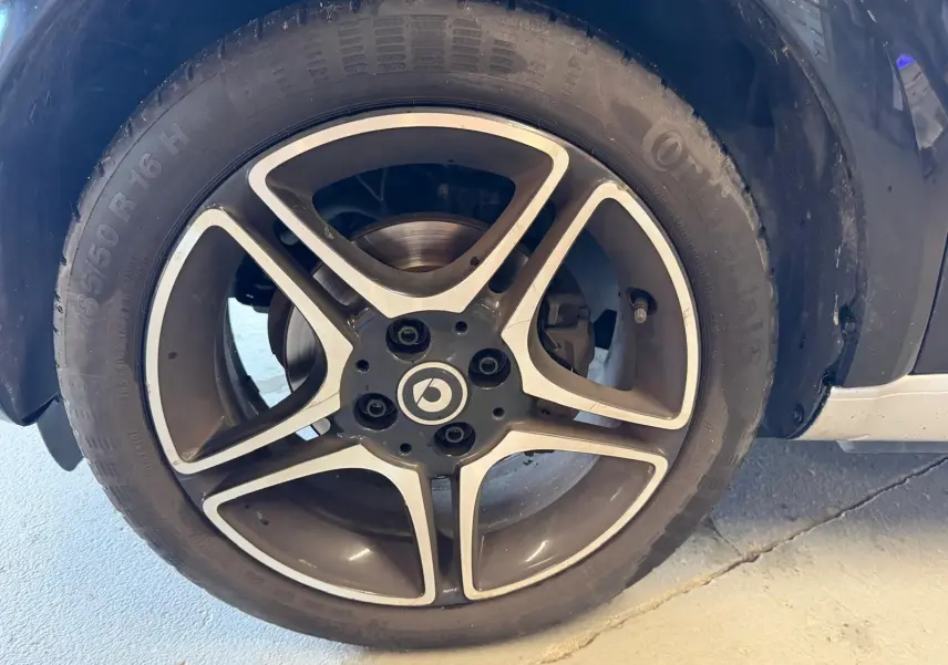 Gros plan sur la jante alu 16 pouces noire et argentée d'une Smart Fortwo Cabrio noire, vue côté roue arrière.