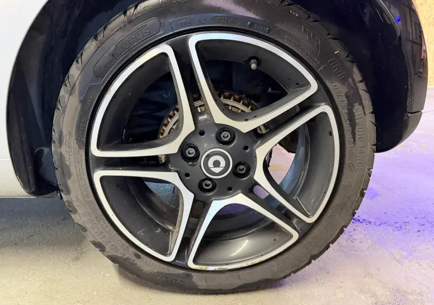 Gros plan sur la jante alu 16 pouces noire et argentée d'une Smart Fortwo Cabrio 2019, avec pneu visible.