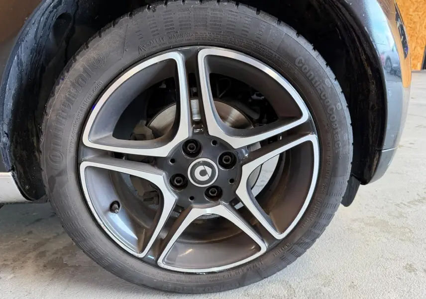 Gros plan sur la jante alu 16'' noire et argentée du côté avant droit d'une Smart Fortwo Cabrio 2019 noire.