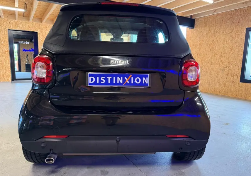 Vue arrière d'une Smart Fortwo Cabrio noire 2019 avec toit souple et échappement visible en intérieur.