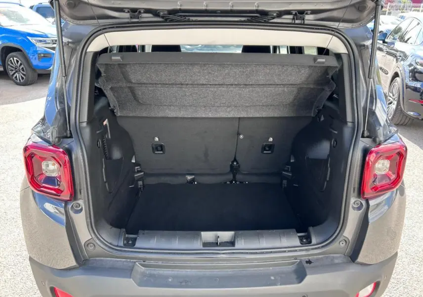 Coffre ouvert vu de l'arrière d'un Jeep Renegade bleu foncé 2023, avec banquette arrière et espace de chargement visible.