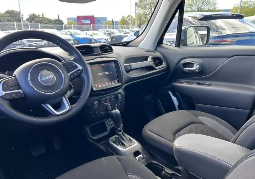 Vue intérieure côté conducteur du Jeep Renegade 2023, montrant le volant, écran tactile et accoudoir central noir.