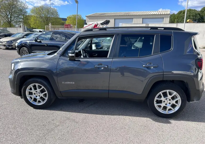Vue de profil côté gauche d’un Jeep Renegade bleu foncé 2023 avec barres de toit et jantes alliage 17 pouces.