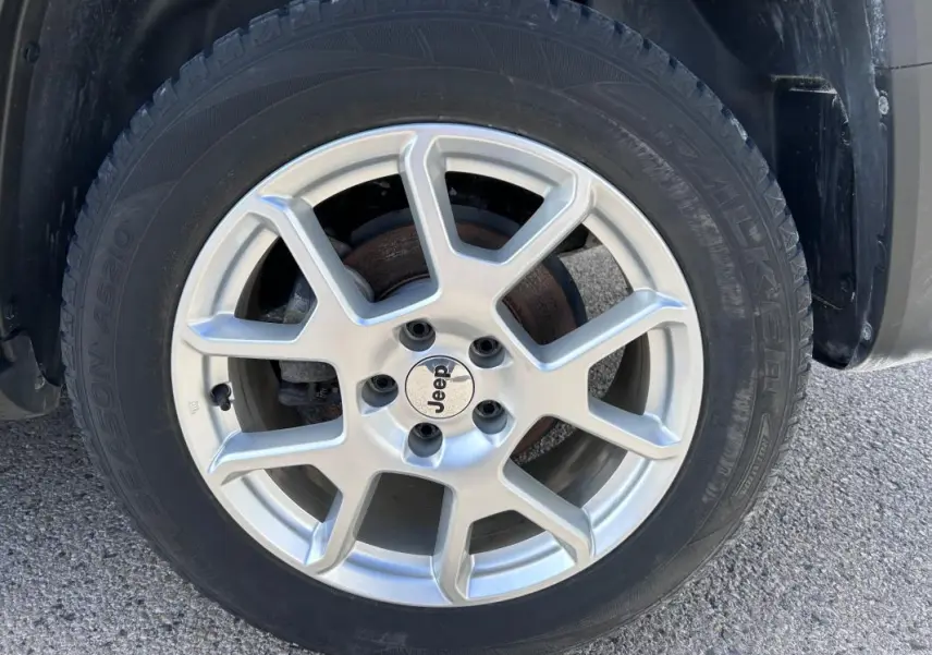 Gros plan sur la jante alliage 17 pouces argentée d’un Jeep Renegade bleu foncé, avec logo Jeep au centre.