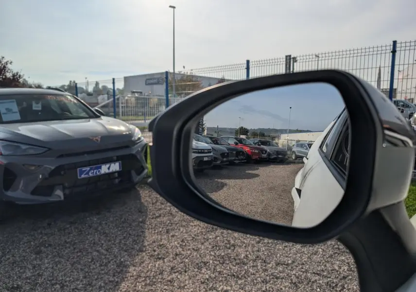 Rétroviseur côté droit montrant la carrosserie blanche d’un Toyota C-HR 1.8 Hybrid 2024 en extérieur.