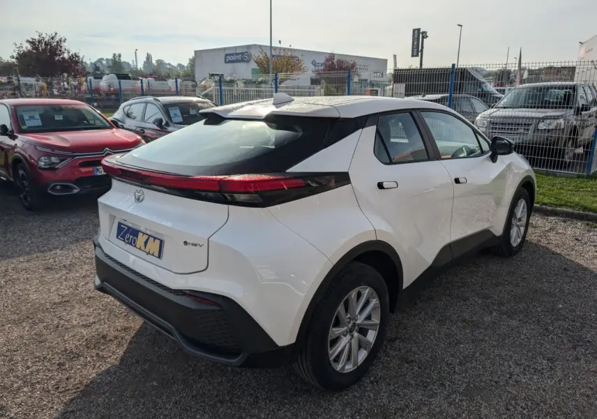 Vue 3/4 arrière droite du Toyota C-HR blanc 2024 avec feux arrière reliés et toit noir contrastant.