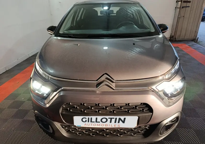 Vue avant d'une Citroën C3 gris foncé 2024 avec phares LED allumés dans un garage fermé.