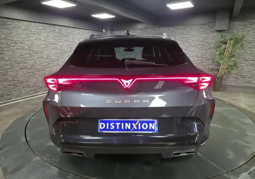 Vue arrière d'une CUPRA Formentor gris métallisé avec bandeau lumineux arrière Tri-LED et double sortie d'échappement noire.