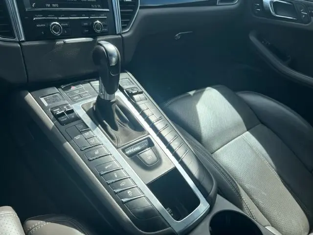 Vue rapprochée de la console centrale du Porsche Macan gris 2015 avec levier de boîte auto et sièges cuir noirs.