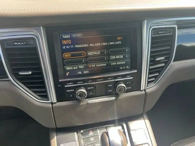 Tableau de bord intérieur du Porsche Macan gris 2015, avec écran central tactile et commandes audio visibles.