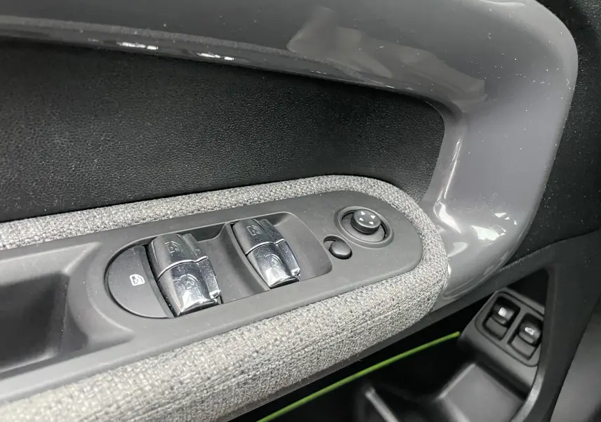 Gros plan sur les commandes de lève-vitres côté gauche d'une MINI Countryman bleu Island Metal avec habillage tissu gris.