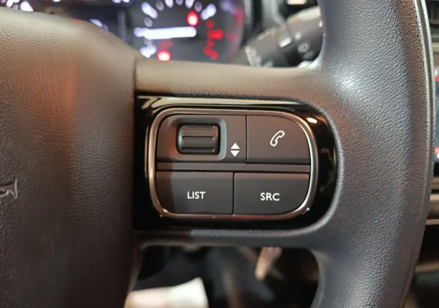 Gros plan sur les commandes gauche du volant noir multifonctions de la Citroën C3 2024 Diesel.