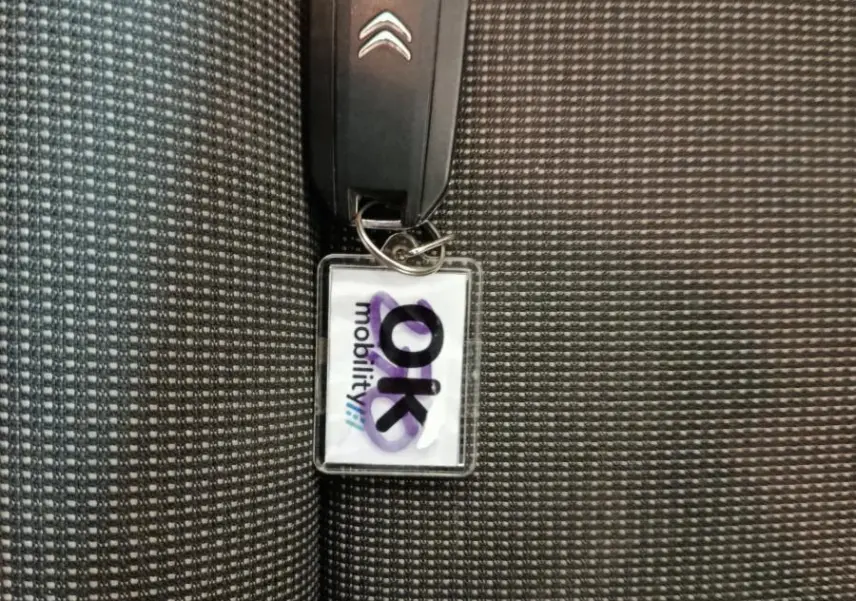 Clé de voiture Citroën posée sur un siège tissu noir à motifs gris avec surpiqûres jaunes visibles.