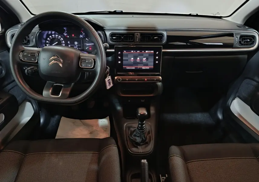 Vue intérieure avant de la Citroën C3 2024 noire, avec tableau de bord central tactile et volant multifonctions réglable.