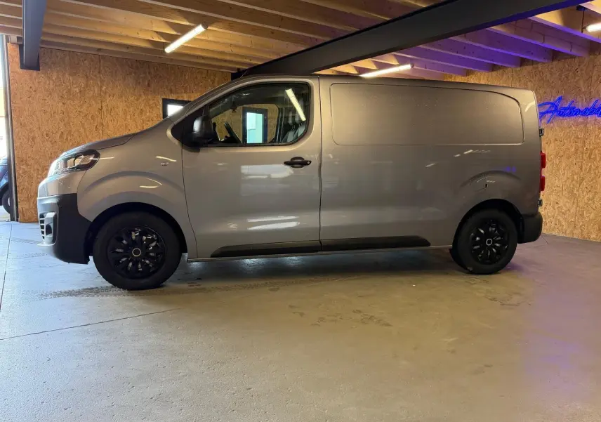 Vue de profil côté gauche d’un Citroën Jumpy gris métallisé 2022 avec porte latérale et jantes noires.