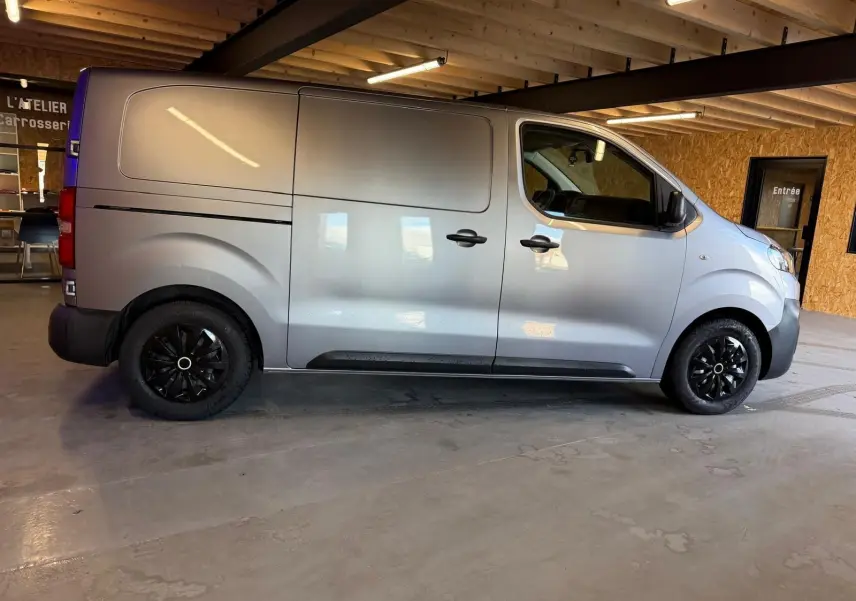 Vue de profil côté droit d’un Citroën Jumpy gris métallisé 2022 avec portes latérales et jantes noires.