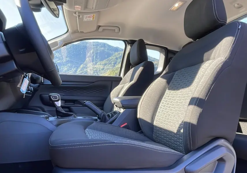 Vue intérieure côté conducteur du Ford Ranger gris iconic 2025, montrant les sièges avant et le volant cuir multifonctions.