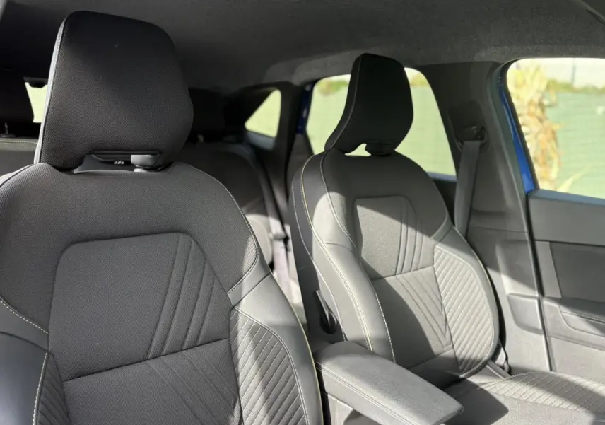 Vue intérieure sur les sièges avant en tissu noir avec surpiqûres blanches du Renault Symbioz E-Tech Full Hybrid 2025.