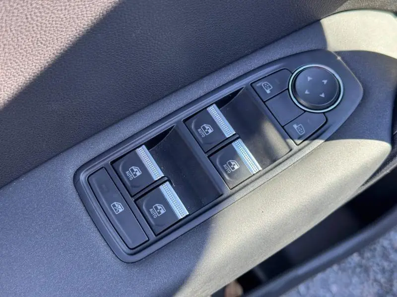 Gros plan sur les commandes des vitres électriques et rétroviseurs côté conducteur du Renault Captur blanc nacré 2025.