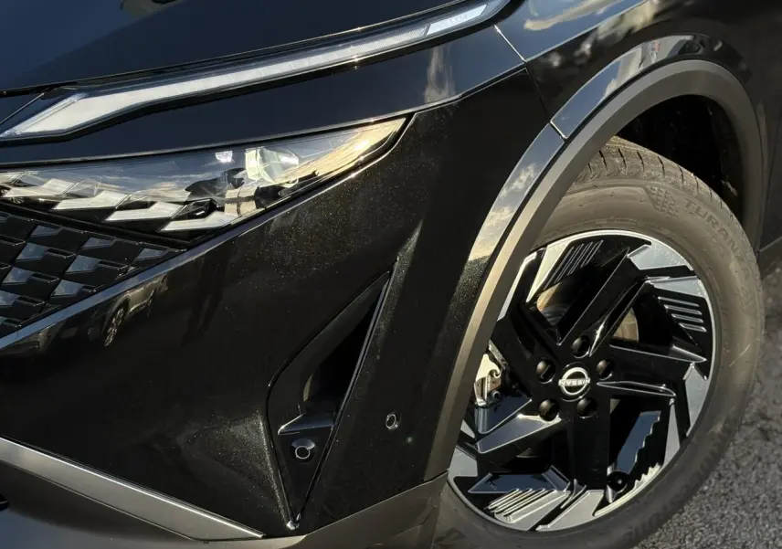 Gros plan sur l'avant droit noir Kuro du Nissan Qashqai III e-Power, mettant en valeur le phare LED et la jante alliage 18 pouces.