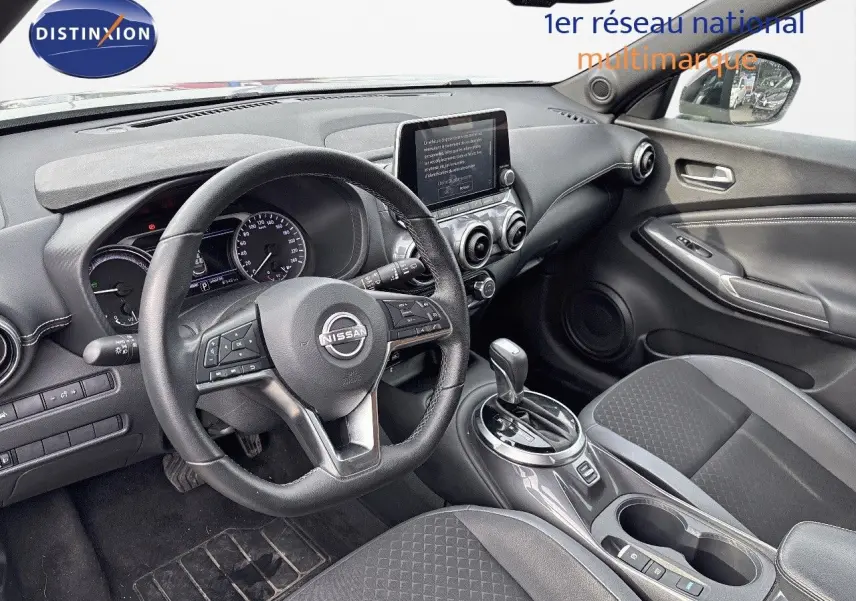 Intérieur avant droit du Nissan Juke 2024 gris perle, volant multifonction, écran tactile et console centrale avec boîte auto.