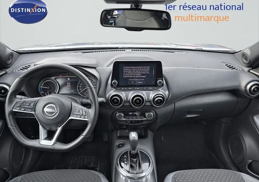 Intérieur du Nissan Juke 2024 gris perle, vue frontale du tableau de bord avec écran tactile et volant multifonction.