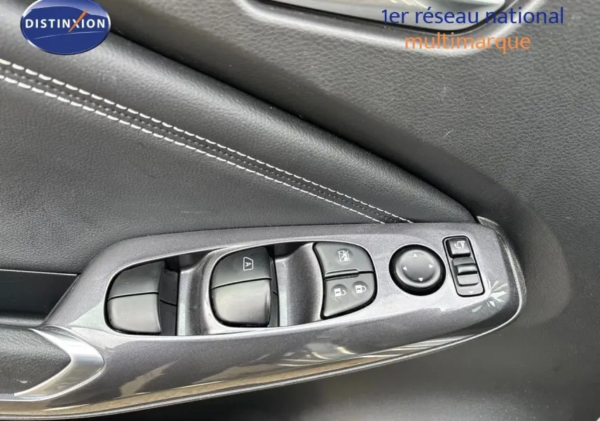 Gros plan sur la commande des vitres côté gauche en plastique gris perle métal avec surpiqûres blanches sur la portière du Nissan Juke 2024.