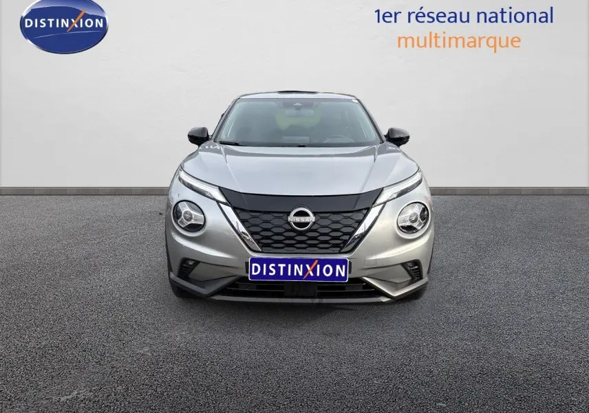 Vue frontale d'un Nissan Juke 1.6 HEV gris perle métal avec calandre noire et phares ronds distinctifs.