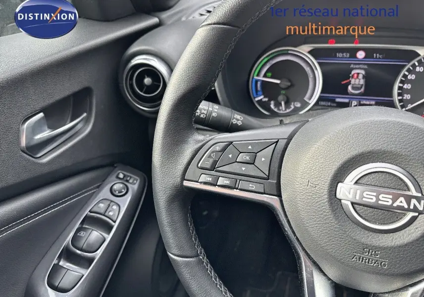 Vue rapprochée du volant et de la portière côté gauche du Nissan Juke gris perle 2024 avec commandes intégrées.