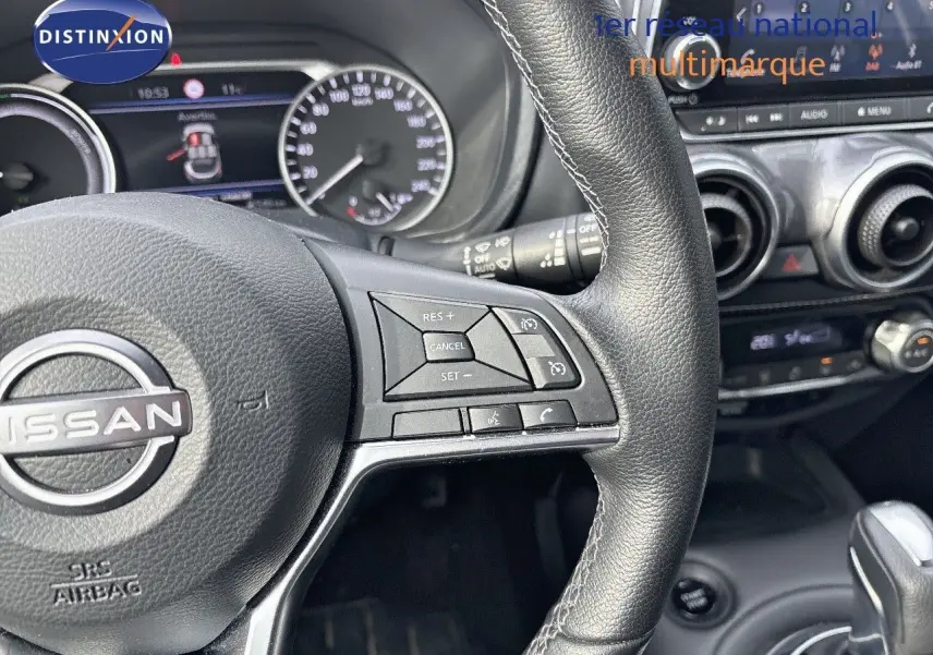 Vue rapprochée du volant en cuir noir du Nissan Juke 2024, avec commandes intégrées et tableau de bord numérique.